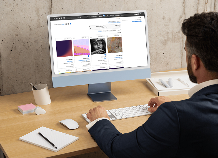 A museum professional viewing artwork thumbnails in an online collections interface on a desktop monitor