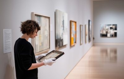 Conservation staff examining a framed artwork in gloves, supporting integrated object management in TMS Conservation Studio.
