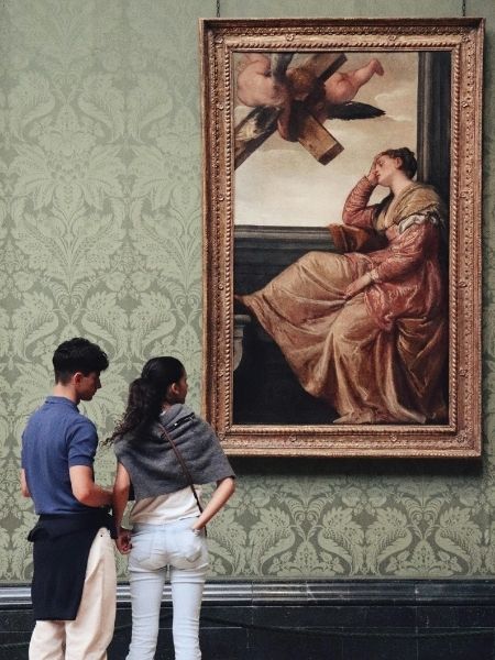Two visitors viewing a framed painting in a gallery, representing the collections institutions manage with TMS Collections