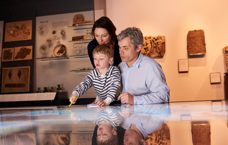 family visiting a museum and looking at an interactive piece
