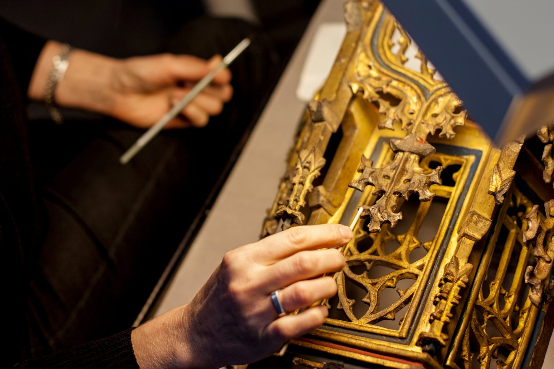 archivist cleaning a gold frame.