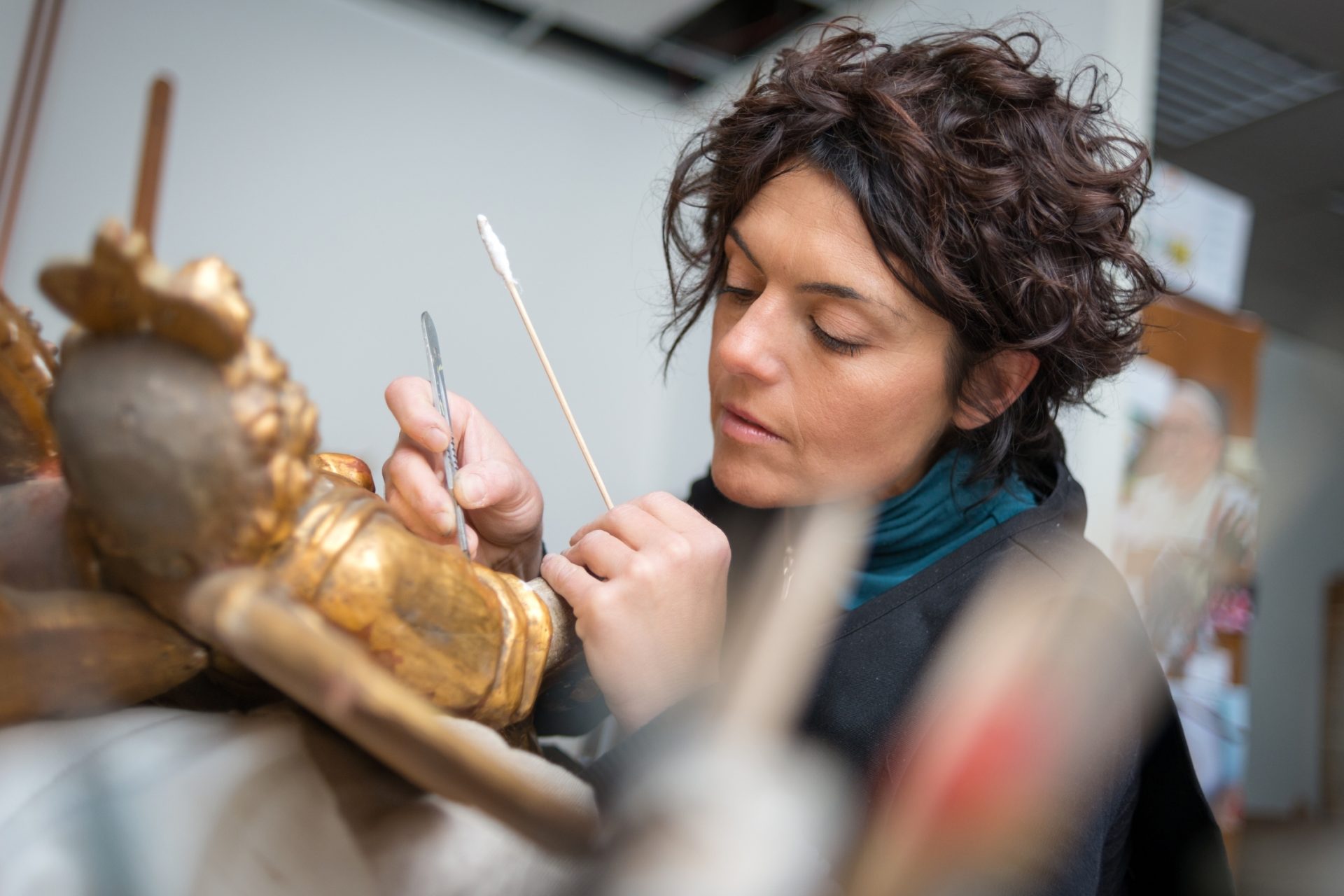 museum archivist cleaning a gold framed artwork.