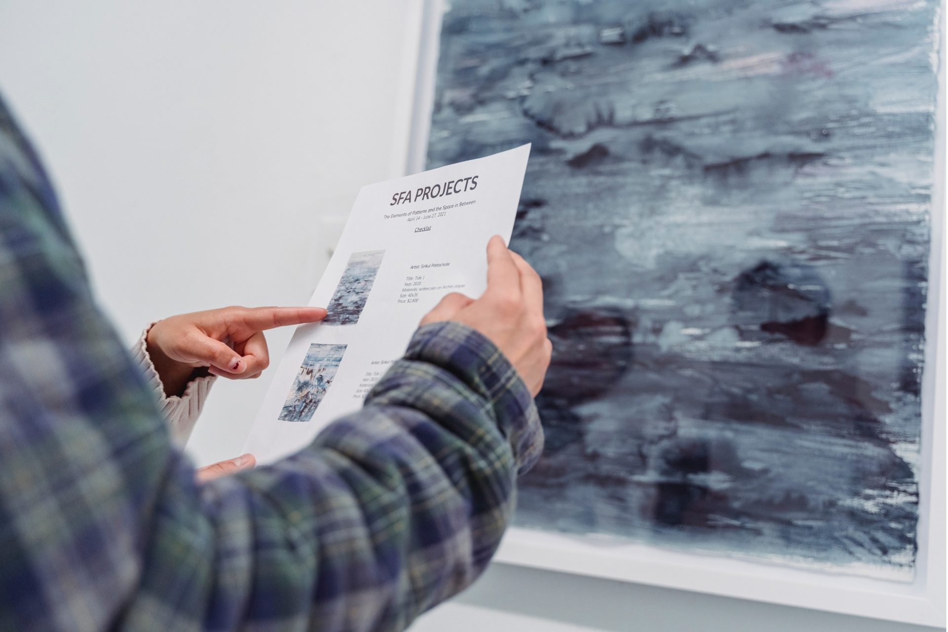 art collectors reviewing the price list for an art exhibition.