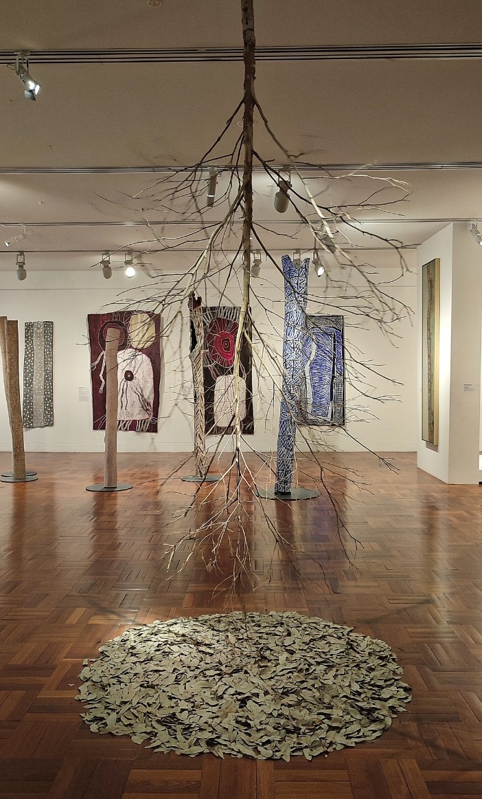 art exhibition with a large sculpture piece hanging from ceiling.