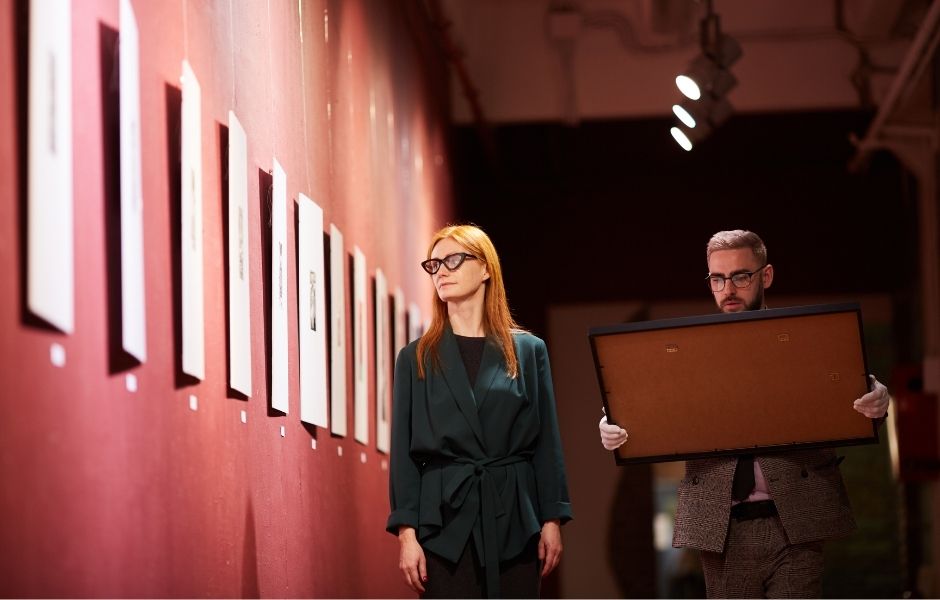Preview of a TMS Media Studio downloadable brochure, depicting collections staff overseeing the installation of a framed work in a red-walled gallery
