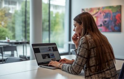 Collections staff reviewing a digital collections site on a laptop in a bright office space with artwork visible on the wall