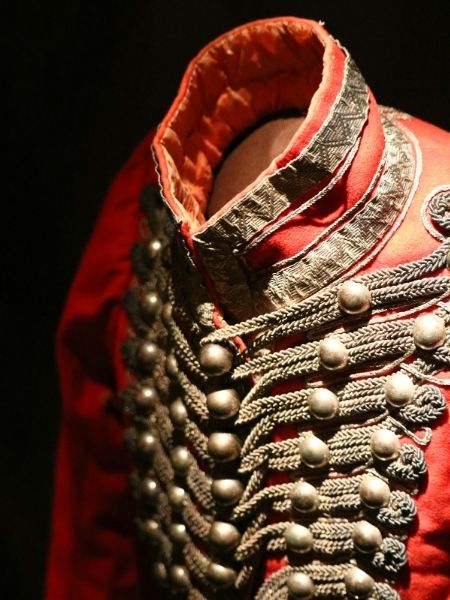 Close-up detail of a historic military uniform with decorative braiding, representing the government and military collections institutions manage with Gallery Systems.