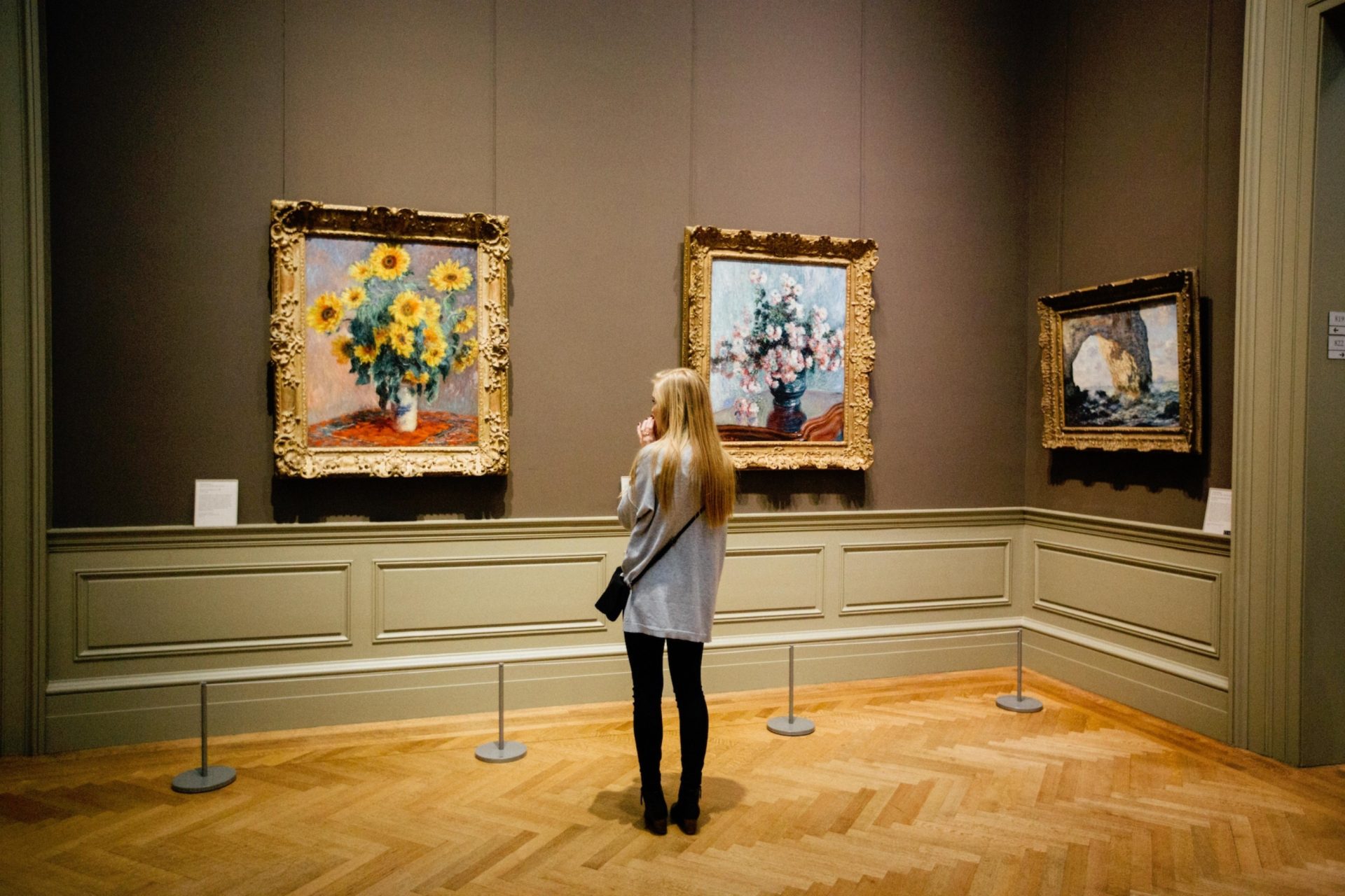 museum visitor looking at three paintings.