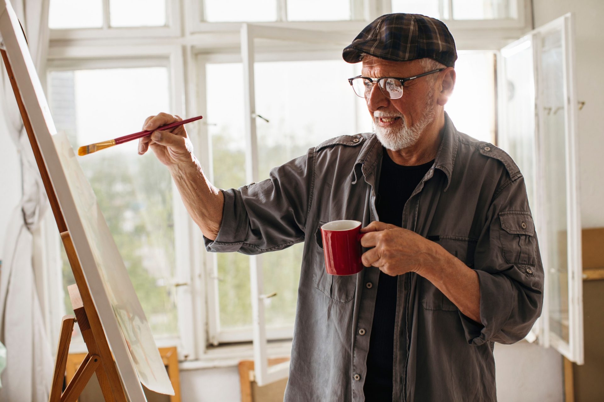 older artist painting at his easel.