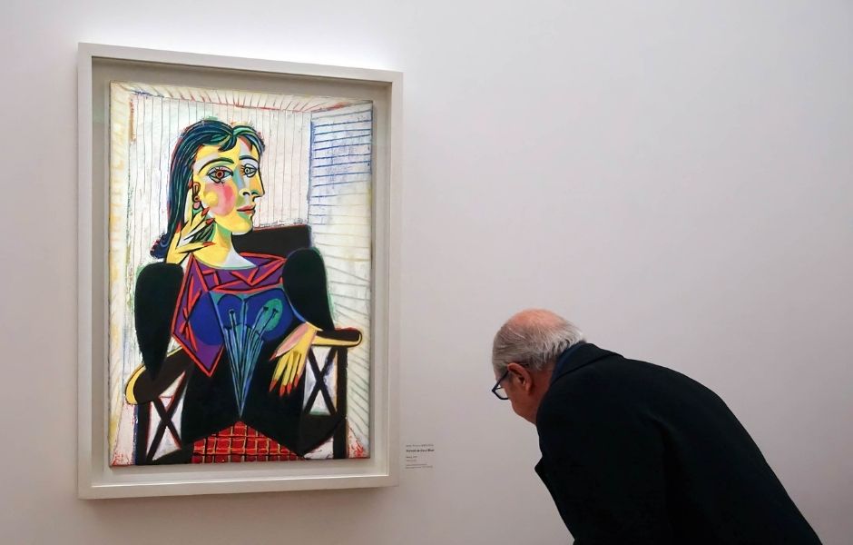 Visitor closely examining a fine art painting in a gallery, representing the fine art collections institutions manage with Gallery Systems.
