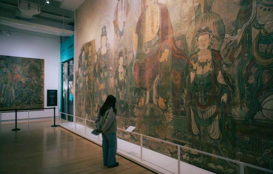 Visitor viewing a large-scale historical mural in a gallery, representing the diverse history collections institutions manage with Gallery Systems.
