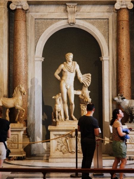 Visitors viewing a classical marble statue in a gallery, representing the diverse collections history institutions manage with Gallery Systems.