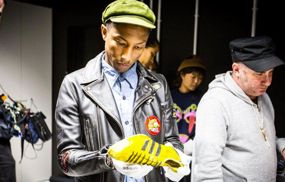 Pharrell Williams holding yellow adidas cleats in the adidas Archive stockroom
