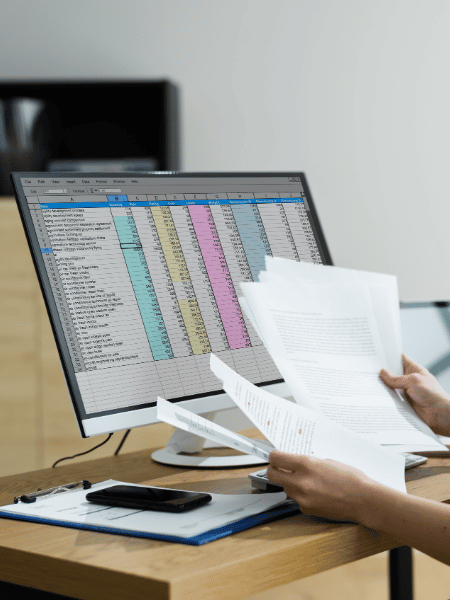 Collections staff comparing printed records with a spreadsheet, reflecting manual processes many institutions rely on.
